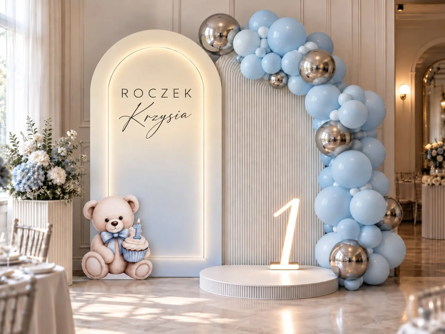 Ścianka na roczek z personalizowanym napisem, girlandą balonów w błękicie i srebrze oraz misiem